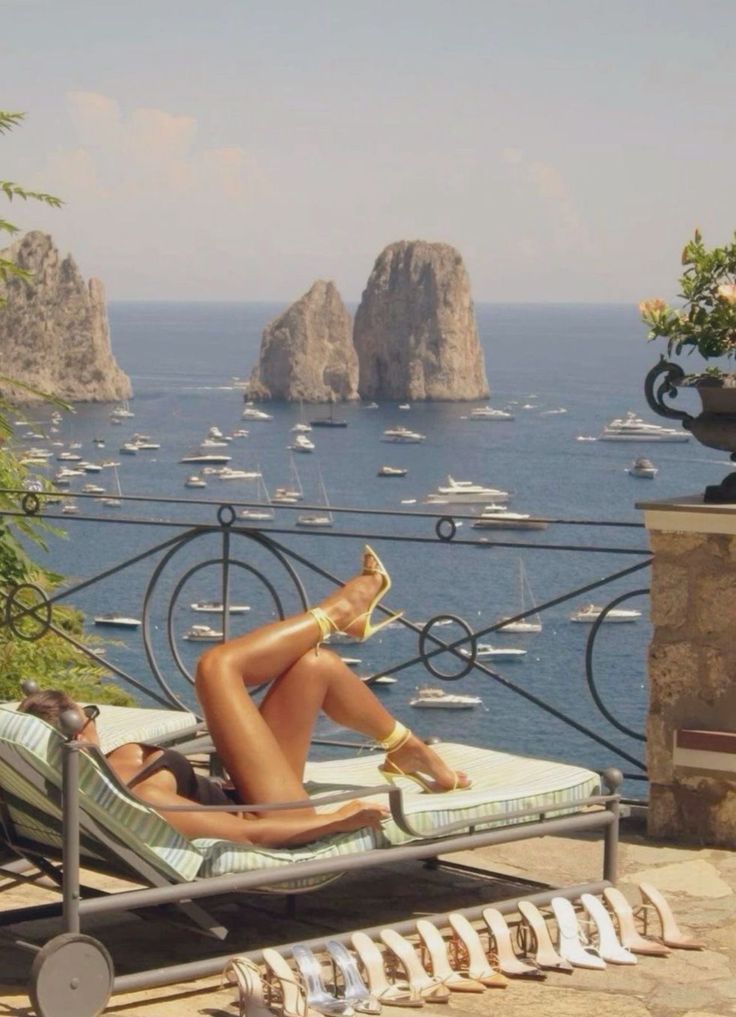Woman in a bikini and high heels sunbathing on a balcony overlooking the ocean