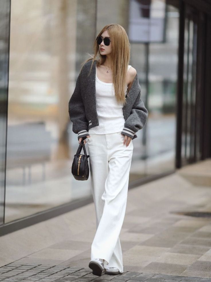 Woman with long hair and sunglasses wearing a white tank top and wide leg pants
