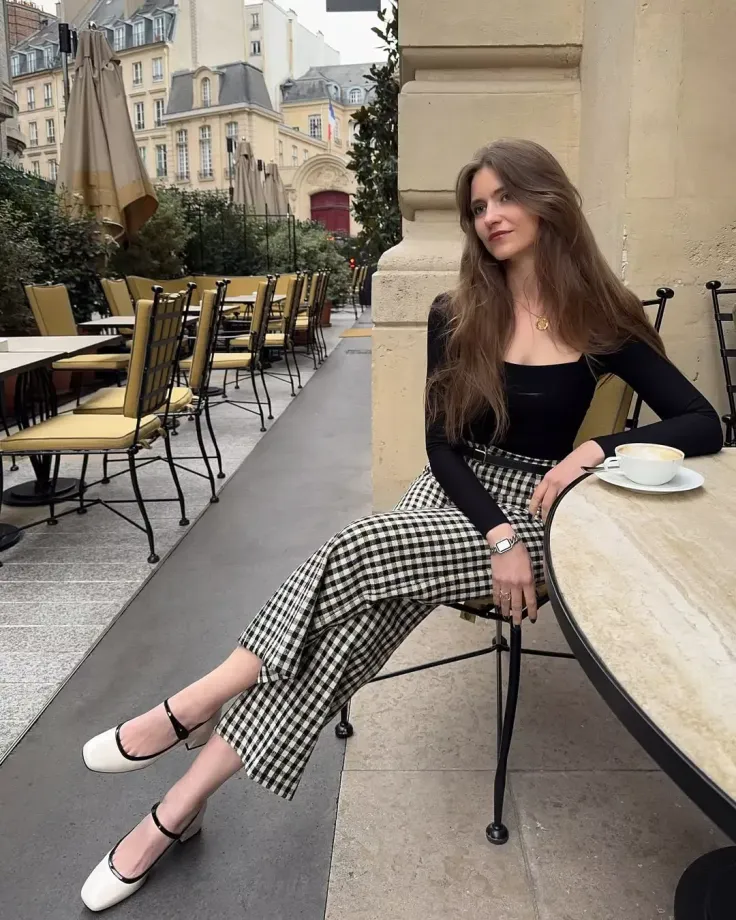 Woman with long hair sitting at an outdoor cafe table