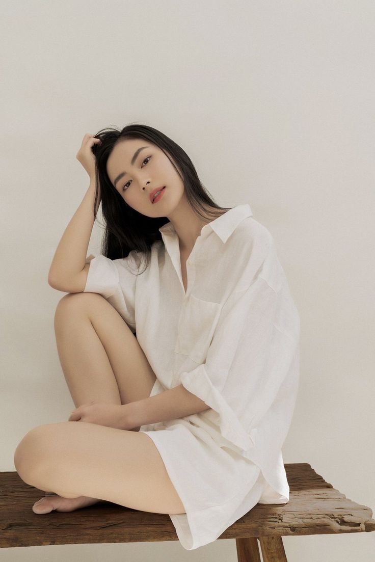 Woman in a white shirt sitting on a wooden bench with exposed legs