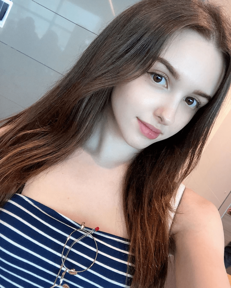 Woman with long brown hair wearing a striped top and glasses