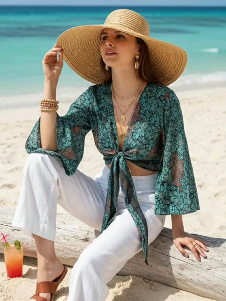 Woman in a straw hat and crop top sitting on a log at the beach