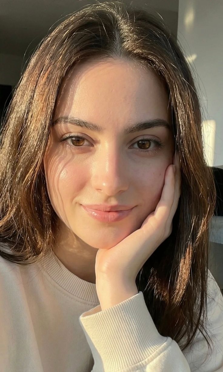 Woman with long brown hair and brown eyes, illuminated by soft natural light