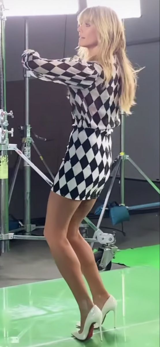 Woman in a black and white harlequin mini dress and white high heels in a studio