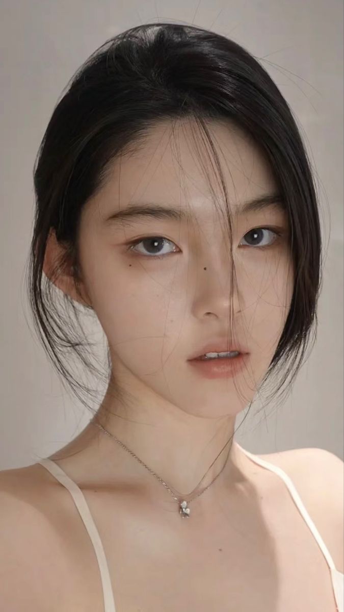 Woman with black hair and a silver necklace, looking directly at the viewer