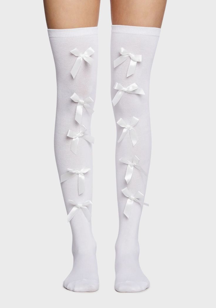 Pair of white thigh-high socks with white bows on a plain background