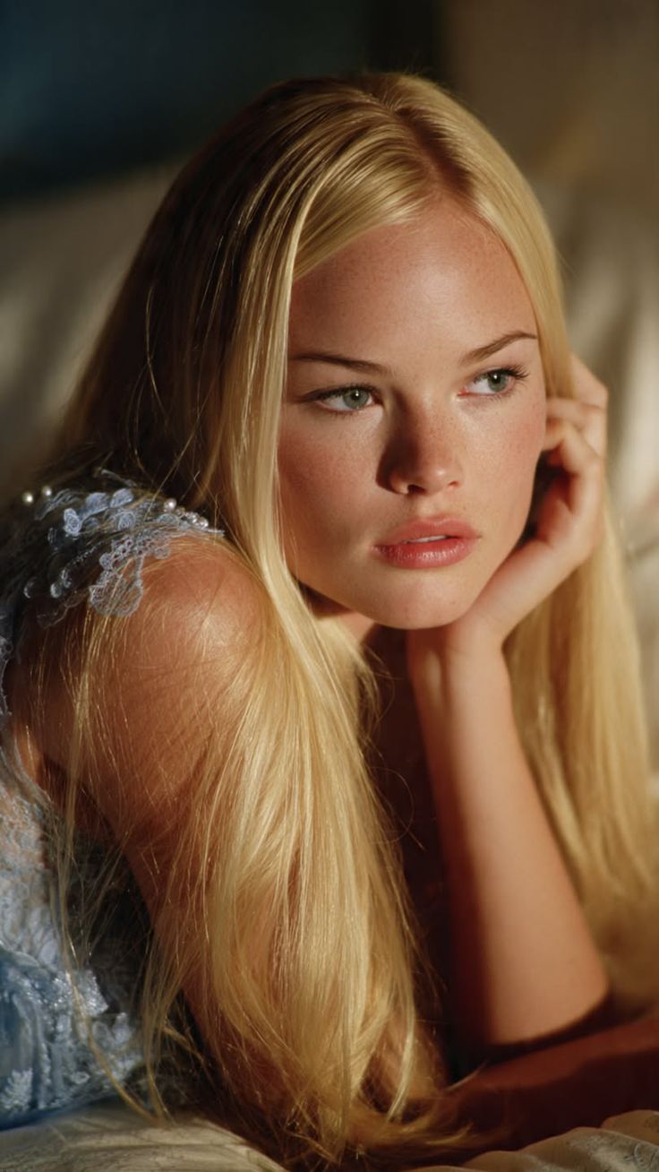 Woman with long blonde hair and freckles wearing a light blue lace top