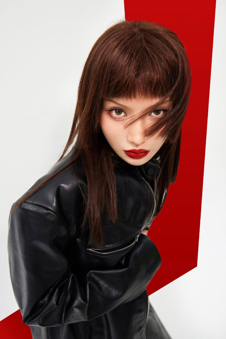 Woman with long dark brown hair and red lipstick wearing a black leather jacket