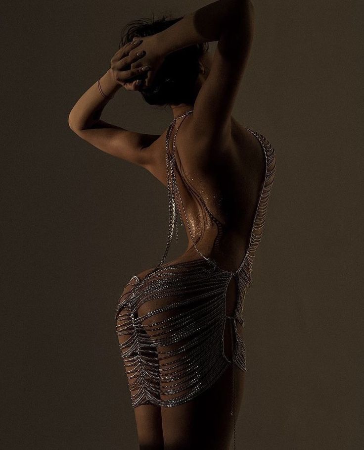 Woman in a chain dress with an exposed back in a provocative pose