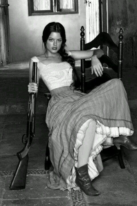 Woman with a shotgun sitting on a chair in a black and white photograph