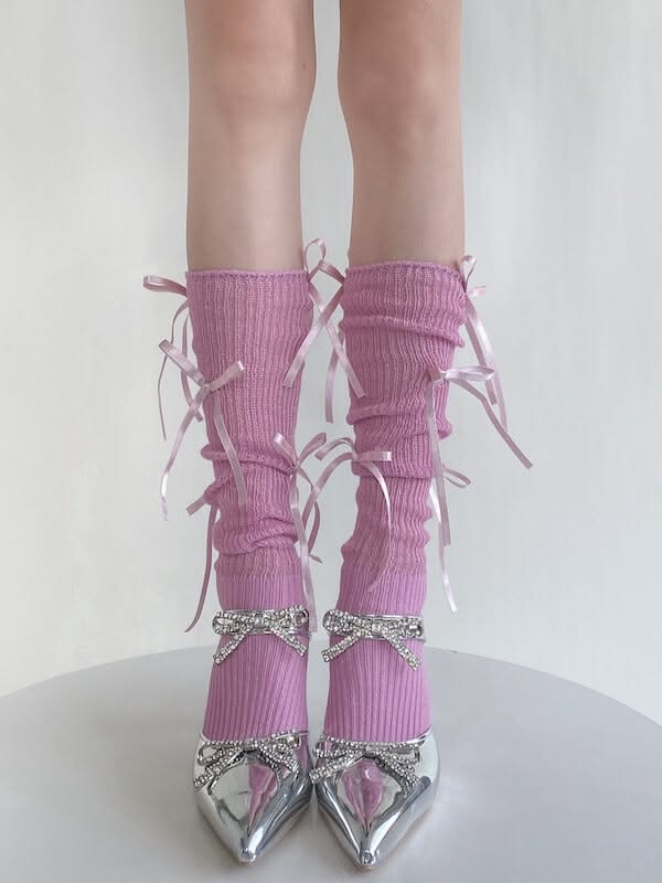 Legs wearing pink socks with ribbons and silver heels with rhinestone bows