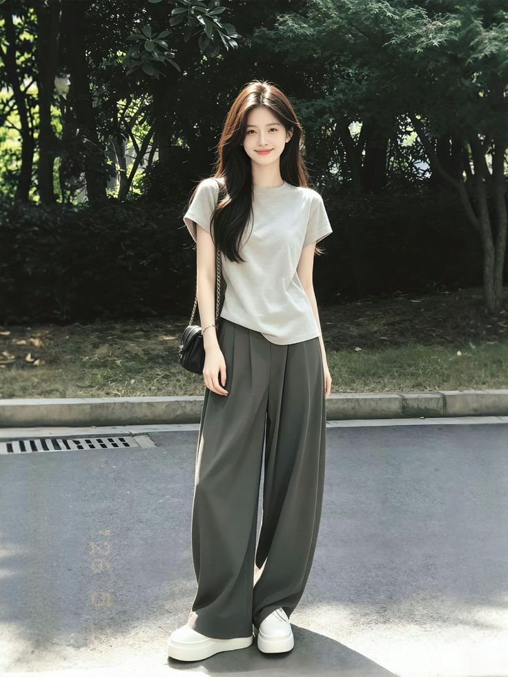 Woman with long dark hair wearing a t-shirt and wide leg pants outdoors