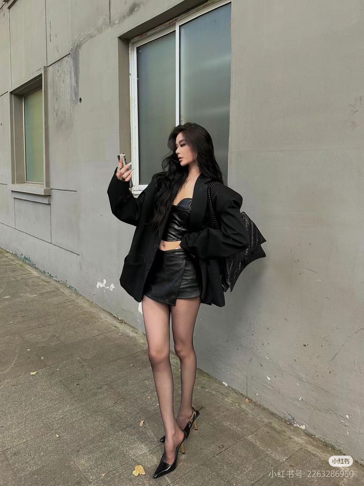 Woman in a black blazer and mini skirt taking a selfie outdoors