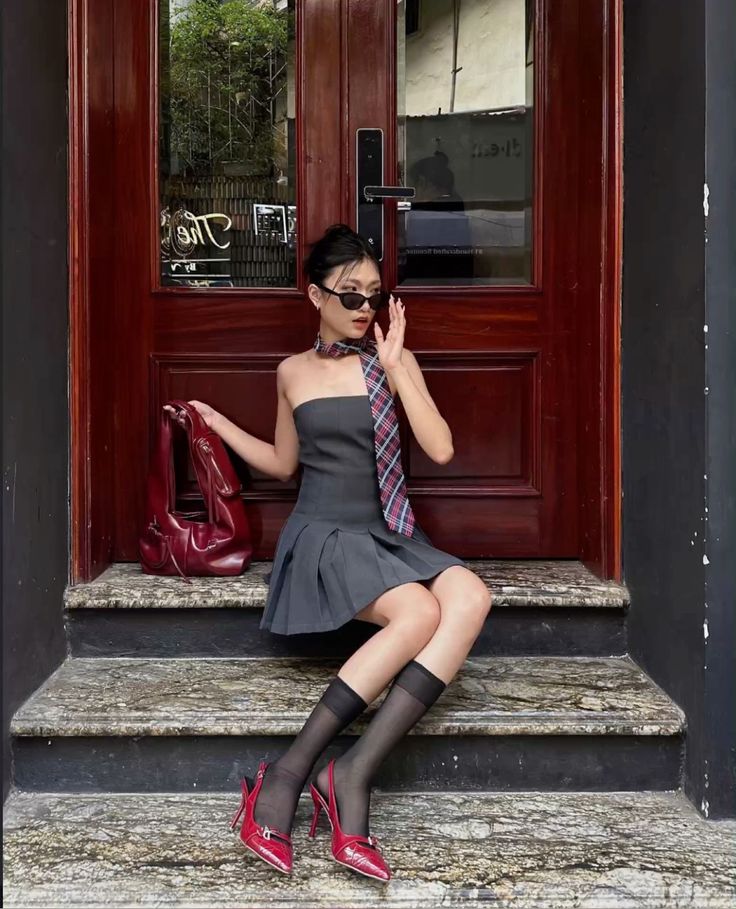 Woman in a strapless dress and plaid tie sitting on steps