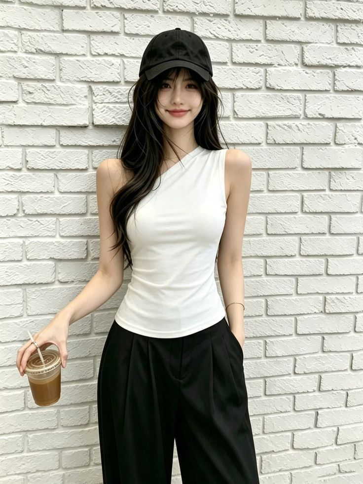 Woman with long black hair wearing a white one-shoulder top and black pants