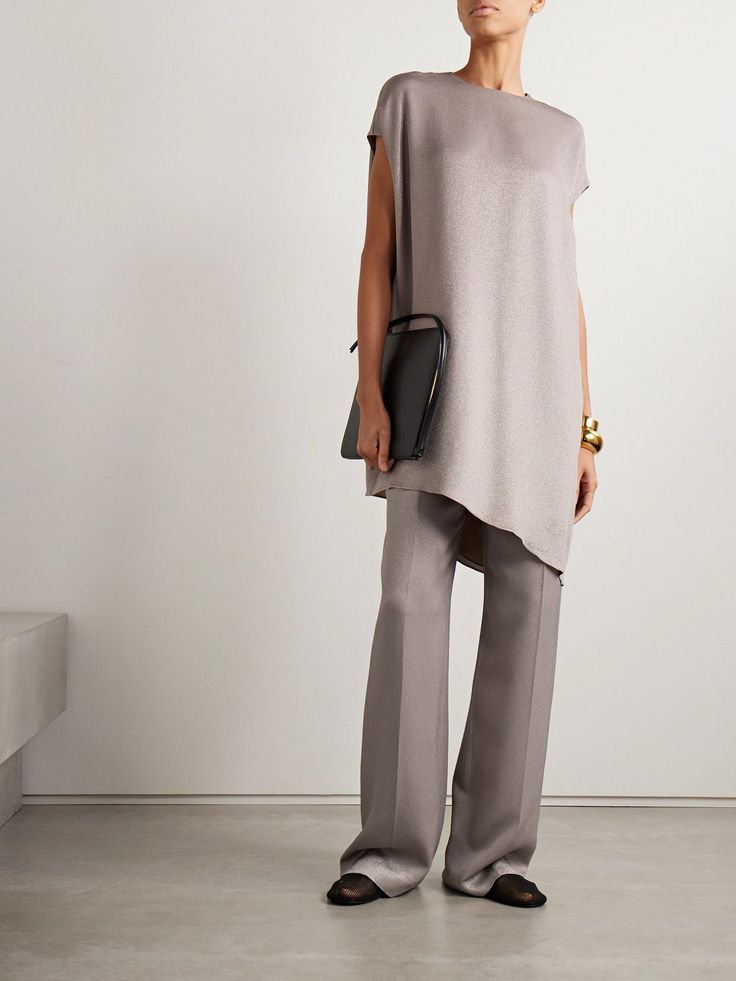 Woman in a tunic top and wide leg pants holding a clutch bag