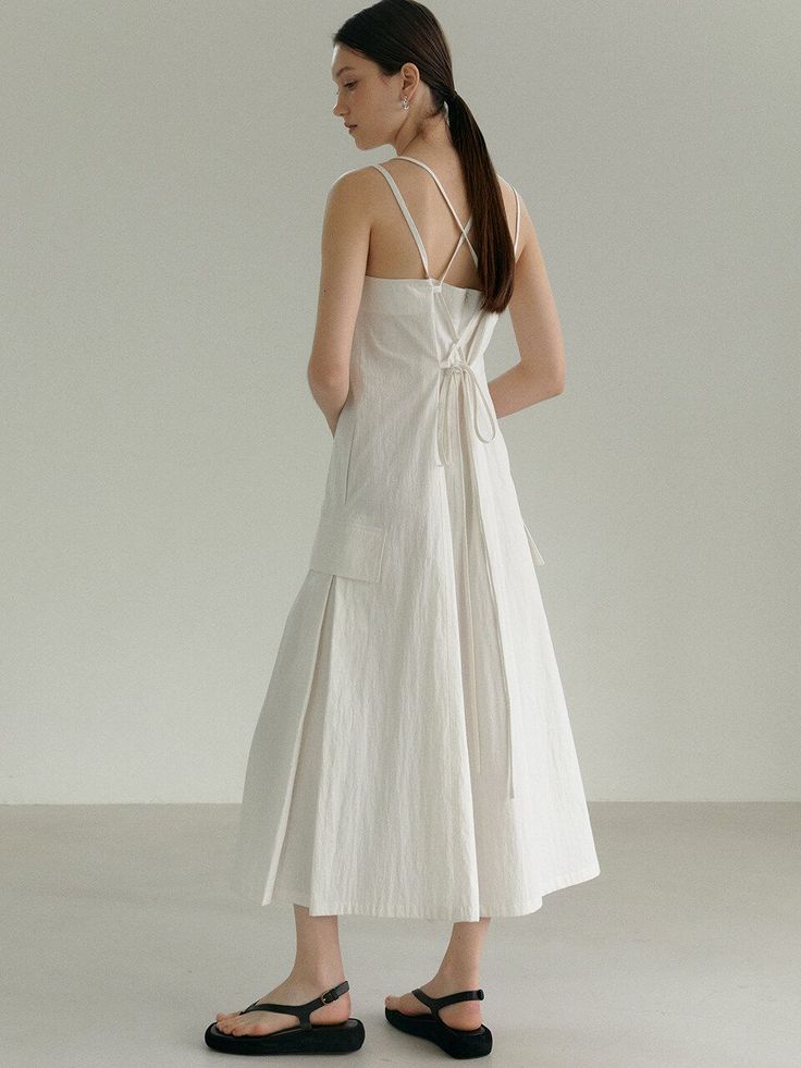 Woman in a white dress with a ponytail standing indoors