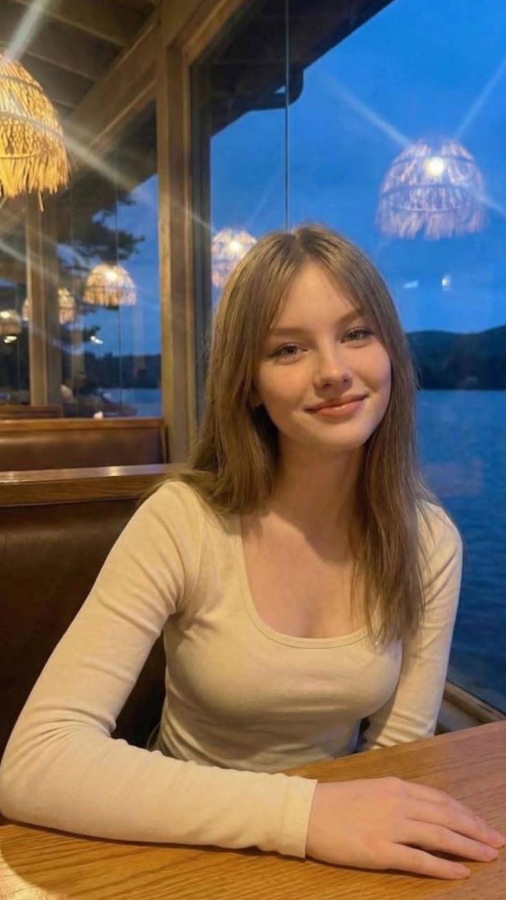 Young woman with long hair smiling in an indoor setting at night