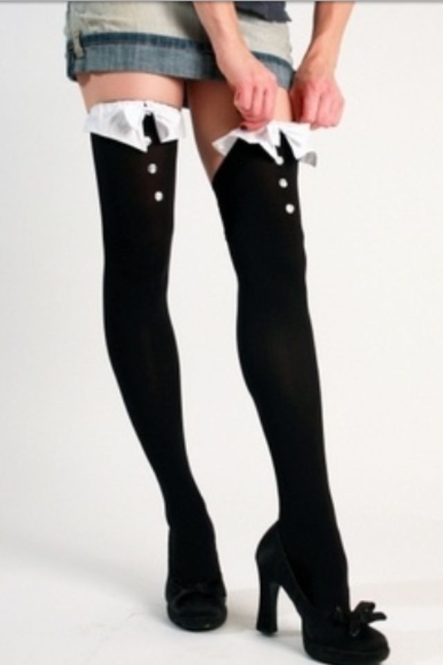 Person adjusting black thigh-high socks with white ruffles and buttons