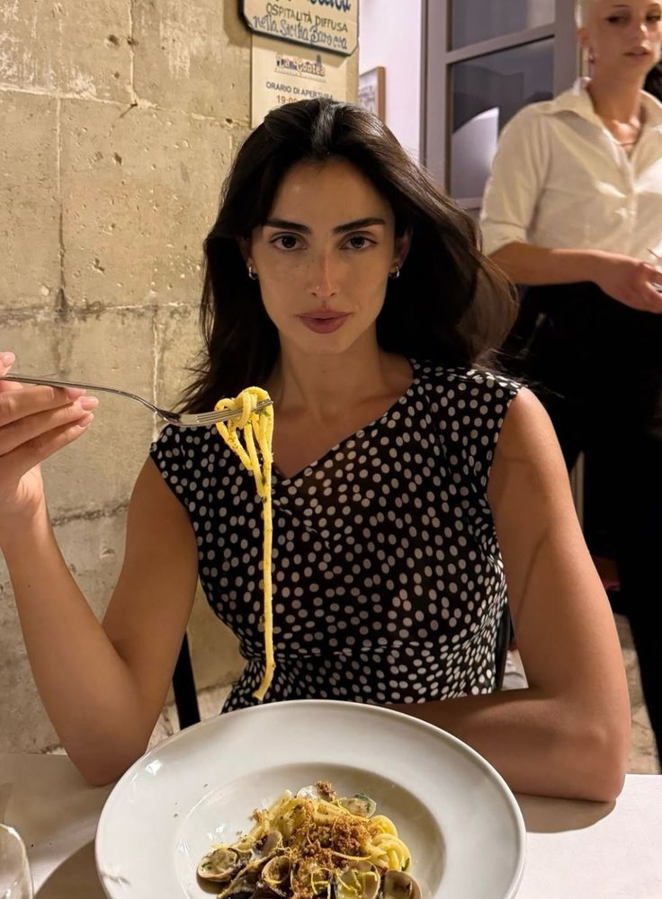 Woman in a polka dot dress eating pasta at a restaurant
