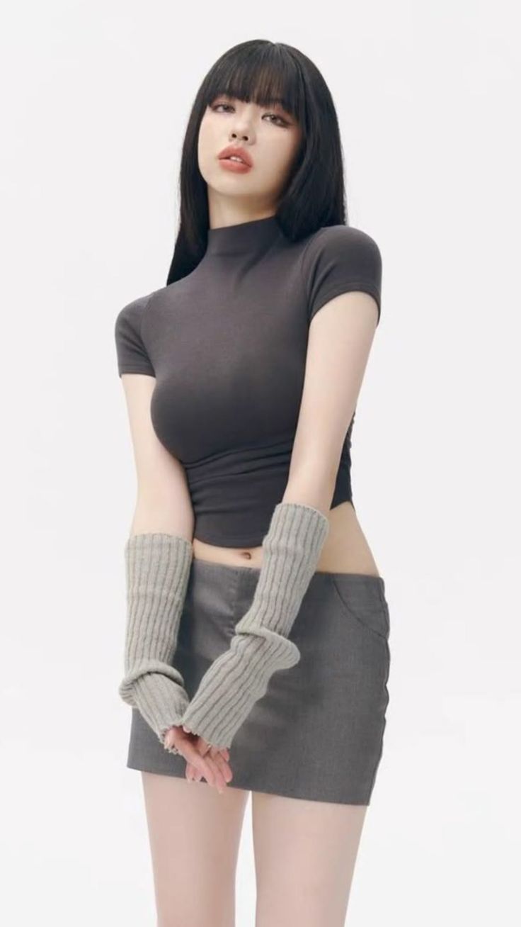 Woman with black hair wearing a cropped top, mini skirt, and arm warmers