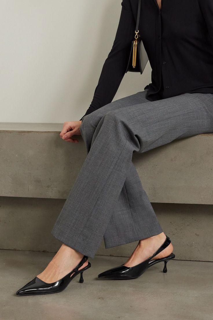 Person in a black shirt and gray pants with black slingback heels