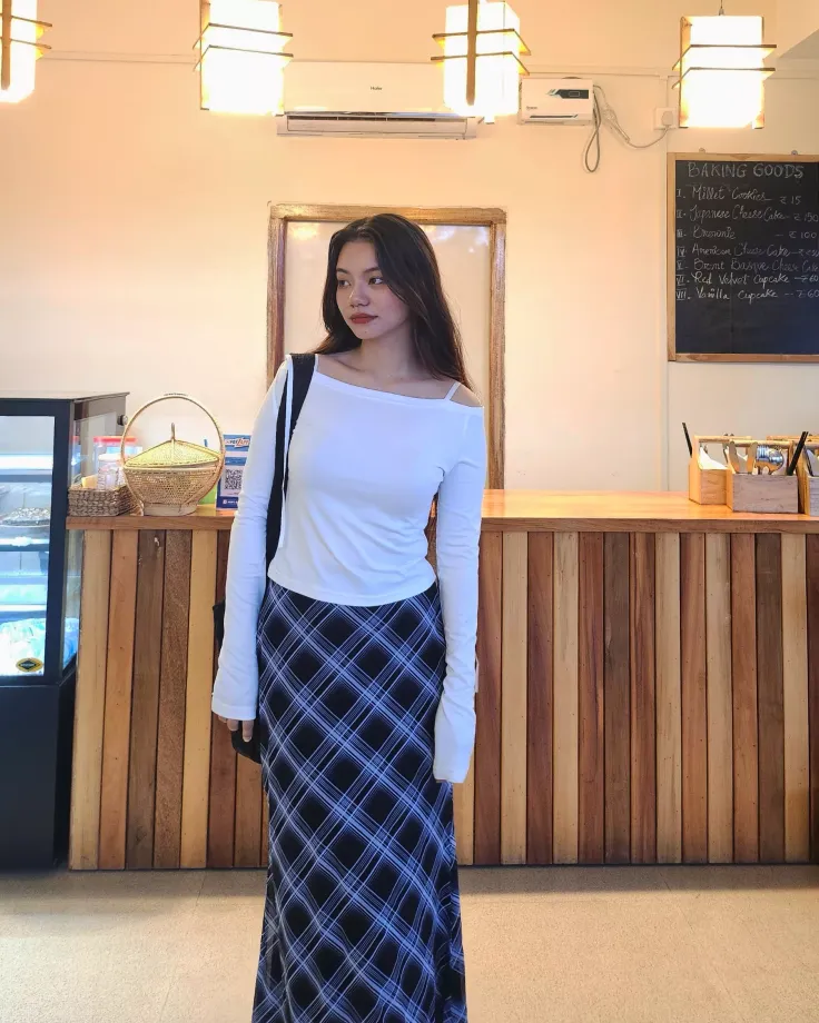 Woman in a white top and plaid skirt standing in a bakery