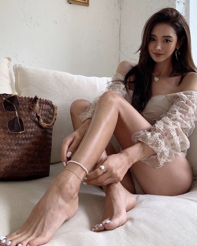 Woman with long hair wearing an off-shoulder top with lace sleeves, sitting indoors