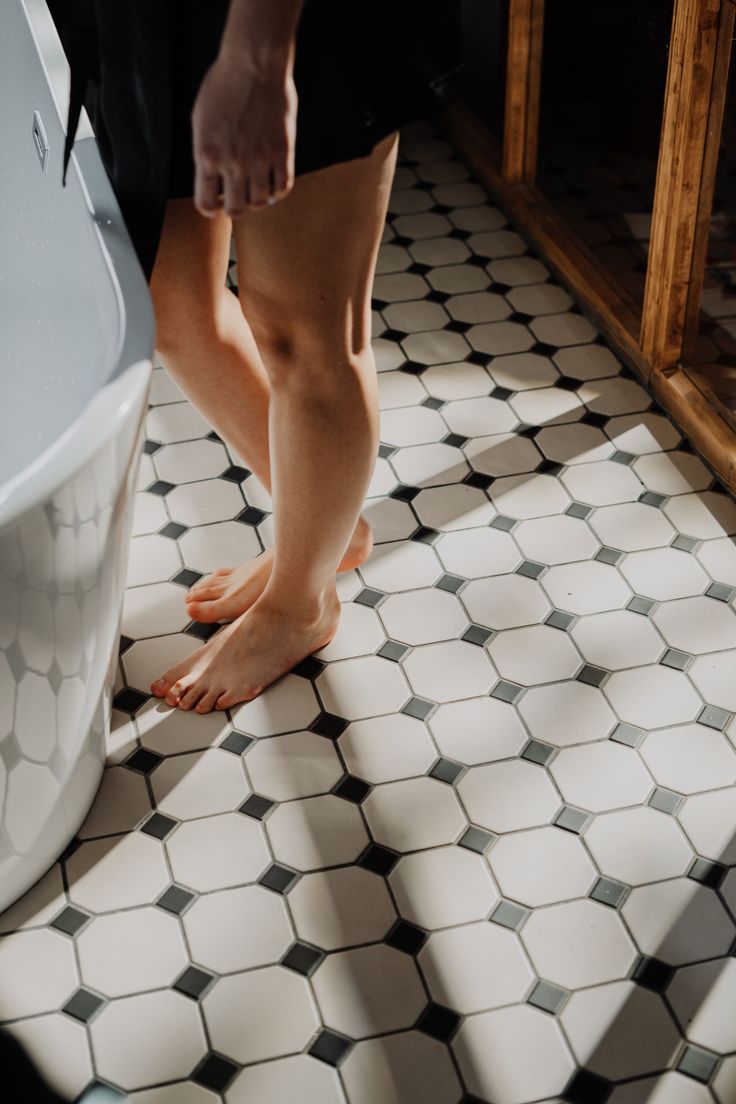 Person standing barefoot on a tiled bathroom floor with soft lighting