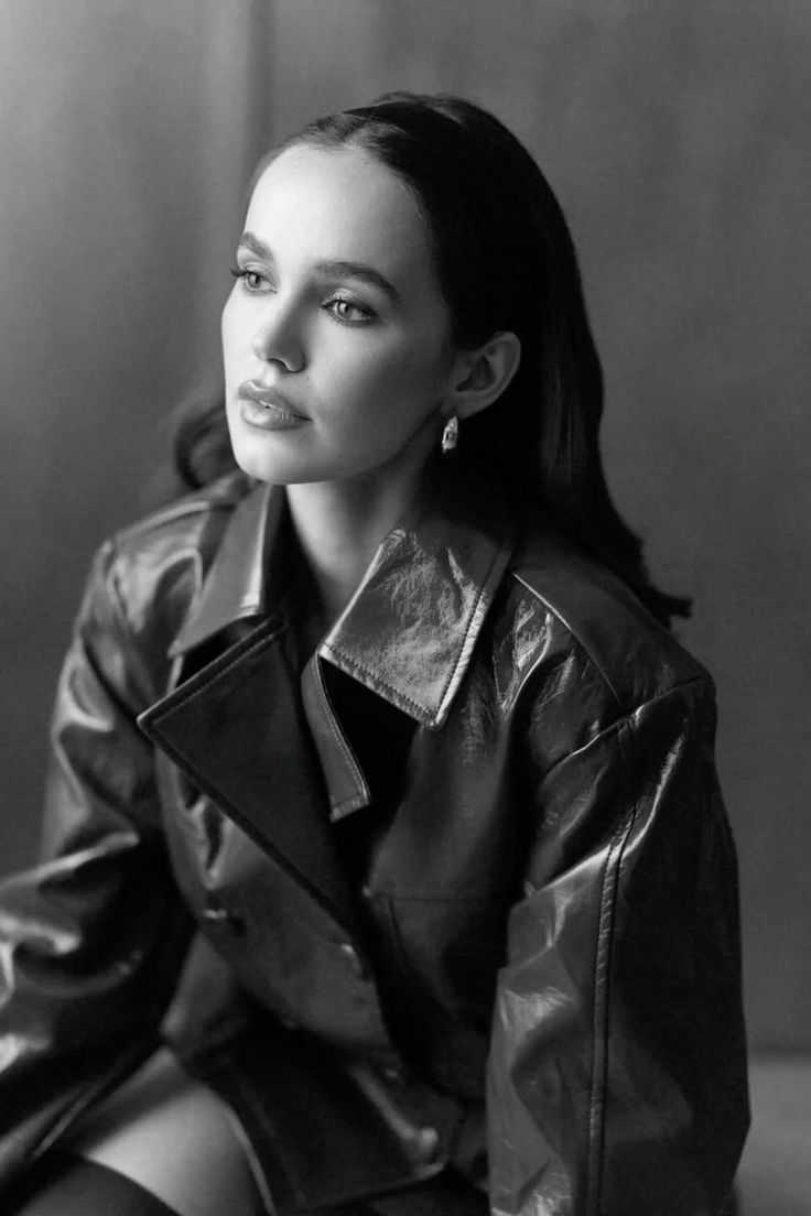 Woman with long hair wearing a leather jacket and earrings in a black and white portrait