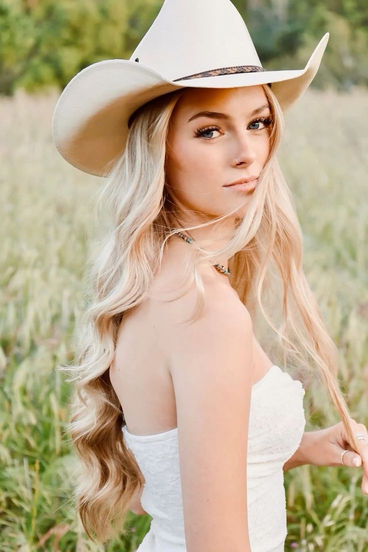 Woman with long blonde hair and a cowboy hat in a field