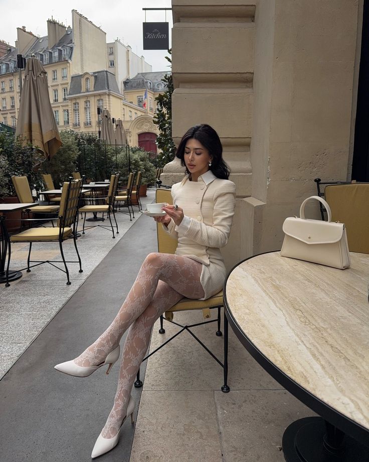 Woman in a white outfit and patterned tights sitting at an outdoor cafe