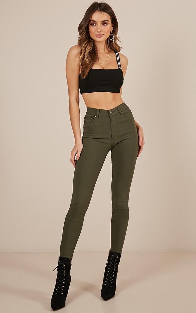 Woman in a black crop top and olive green pants with black lace-up boots