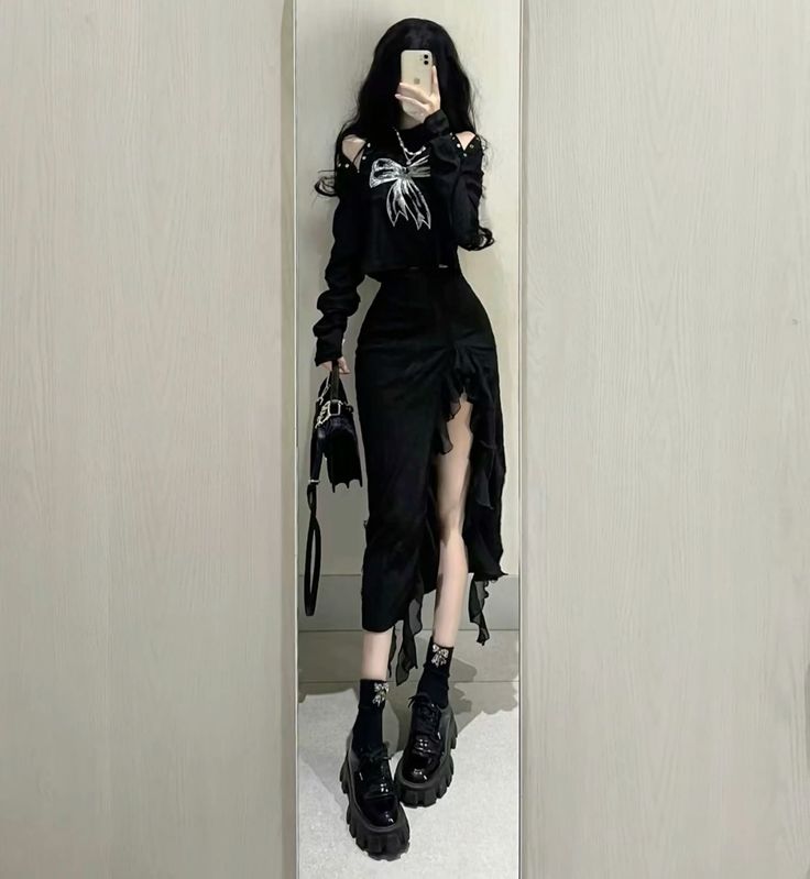 Person in a black outfit with a ruffled skirt and platform shoes taking a mirror selfie