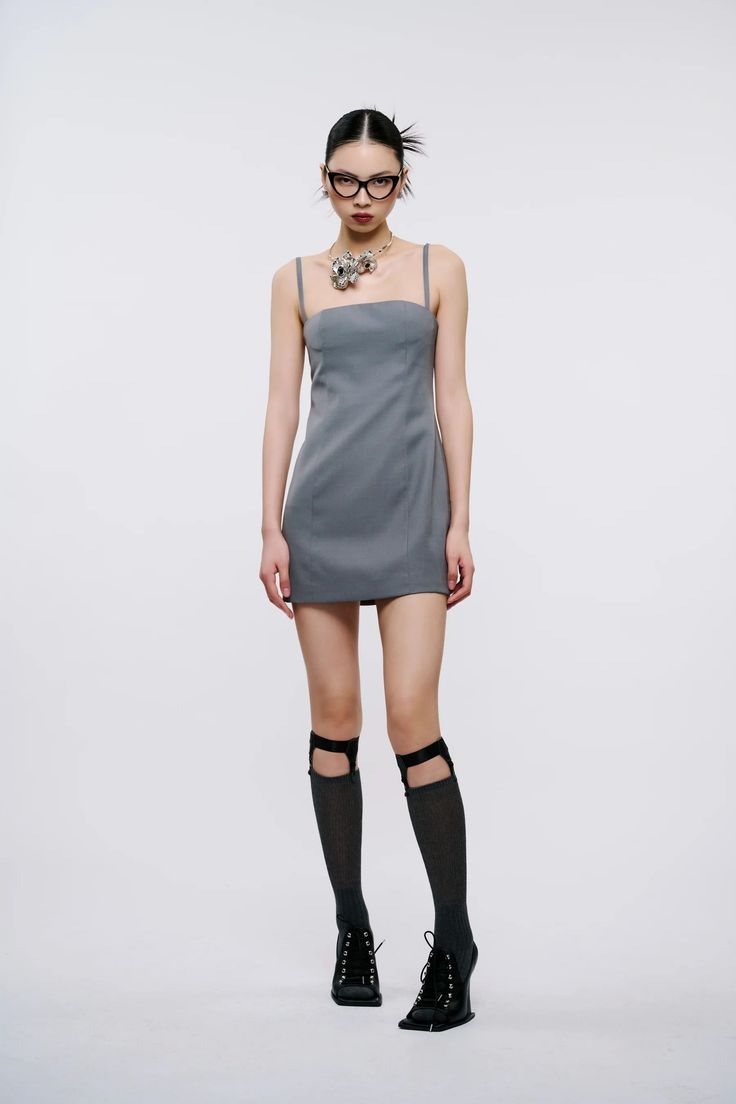 Woman in a gray dress, glasses, and knee-high socks on a white background