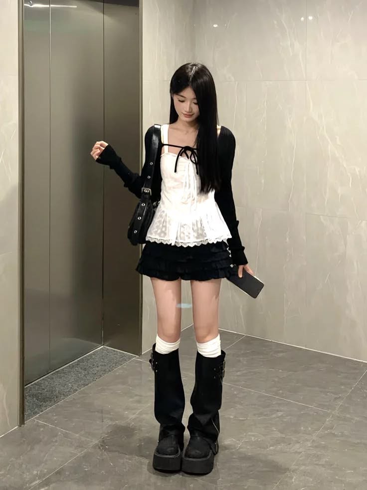Woman with long black hair in a white lace top and black mini skirt indoors