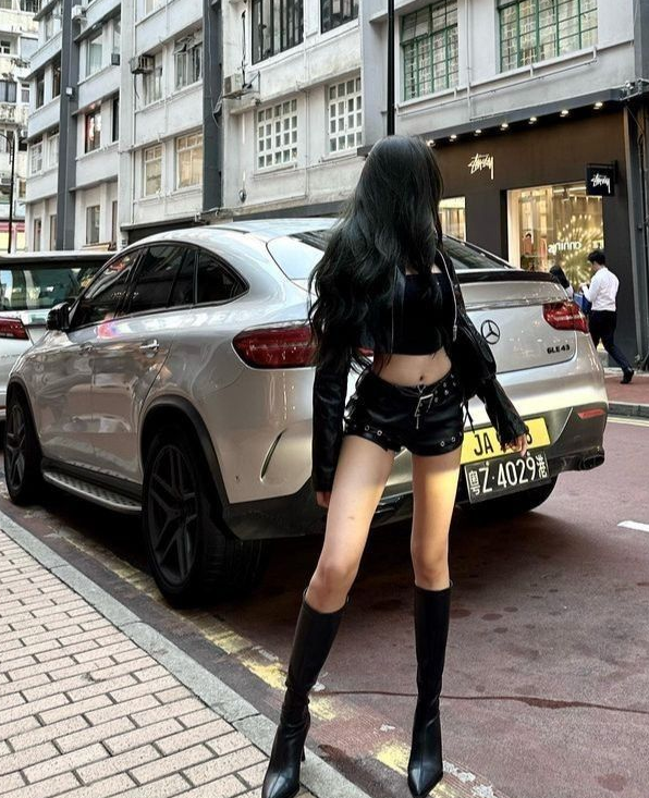 Woman with long black hair in a leather outfit standing on a city street