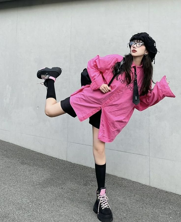 Person in a pink shirt, black shorts, and beret posing outdoors