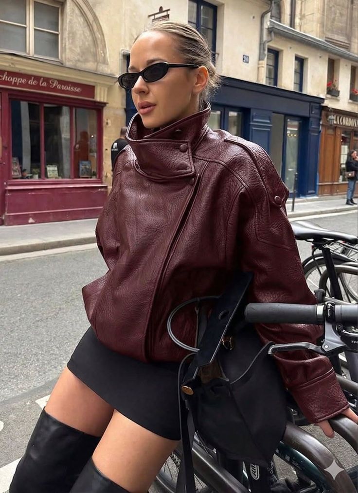 Woman in a maroon leather jacket and black mini skirt on a city street