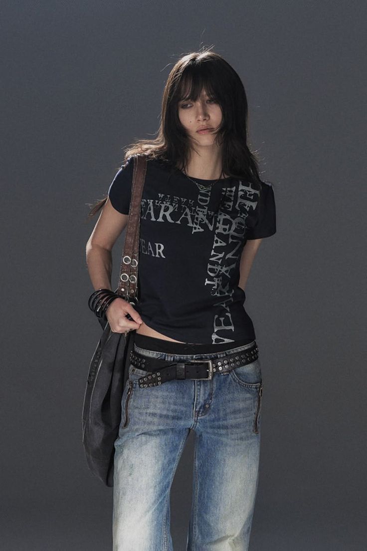Person with long hair wearing a black t-shirt and jeans with a studded belt