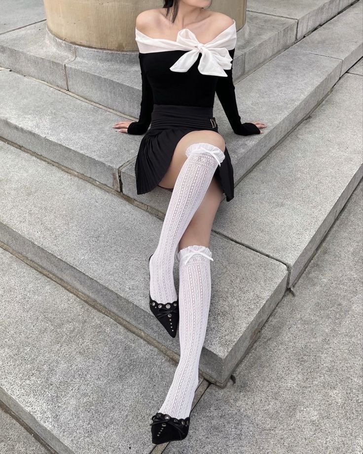 Woman in an off-shoulder top and pleated skirt sitting on stone steps