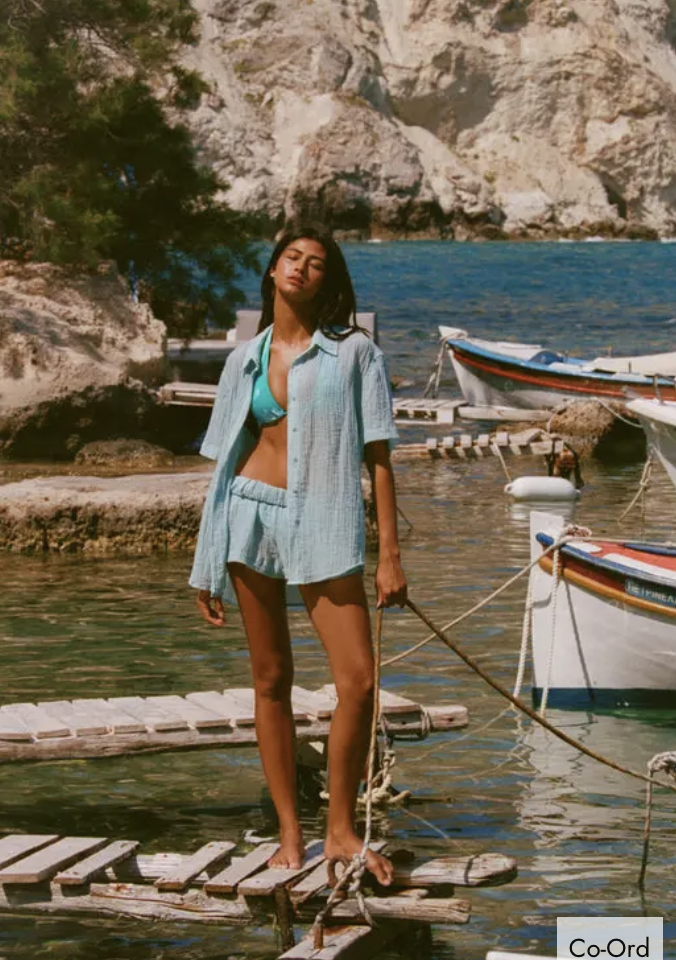 Woman in a bikini top and matching shorts set standing on a wooden pier