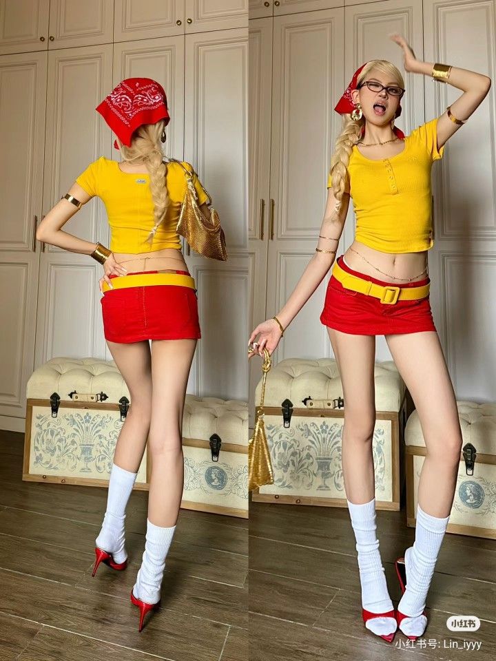 Woman in a red bandana, yellow crop top, and red mini skirt posing indoors