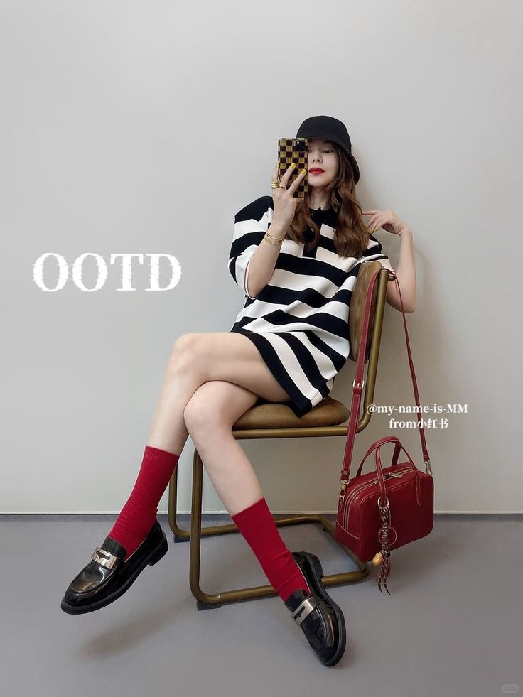 Woman in a striped dress, bucket hat, and red socks sitting indoors