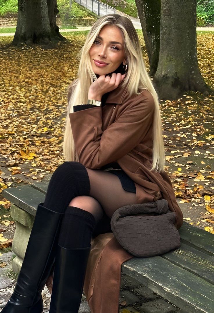 Woman with long blonde hair sitting on a bench in a park with autumn leaves