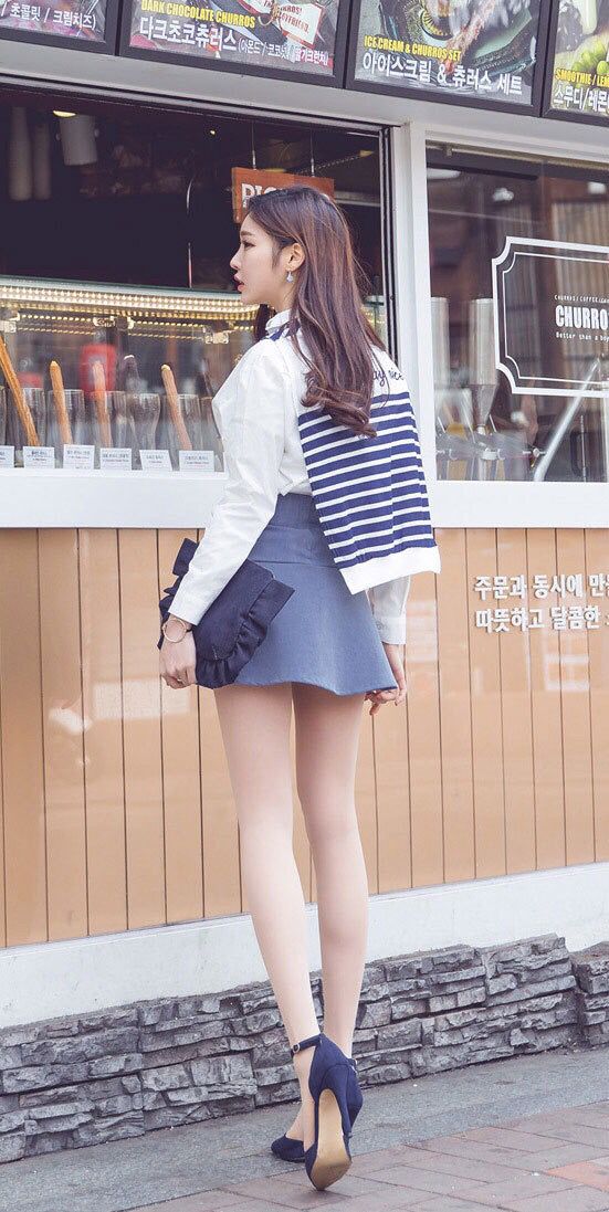 Woman in a white shirt and blue mini skirt standing on a street
