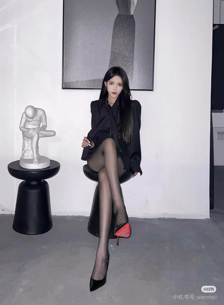 Woman in a black blazer and pantyhose sitting indoors