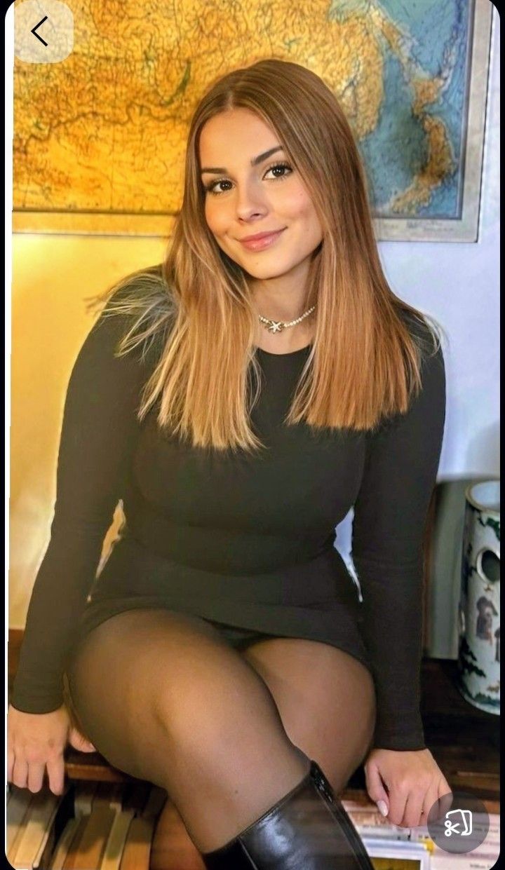 Woman in a black dress and tights, smiling at the camera