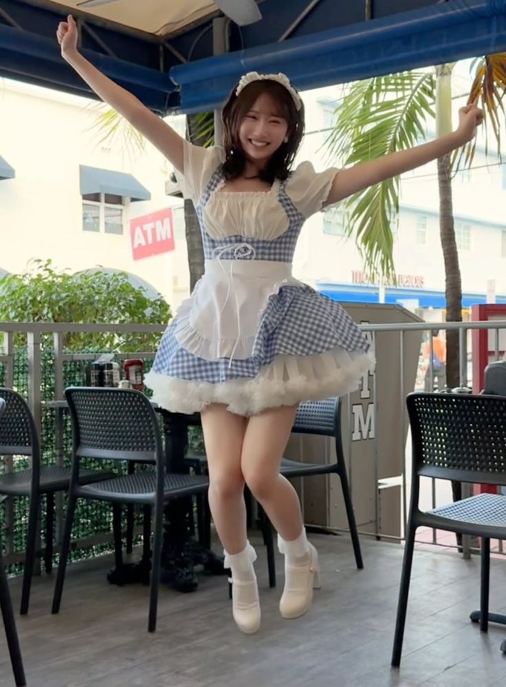 Woman in a blue gingham maid outfit jumping outdoors