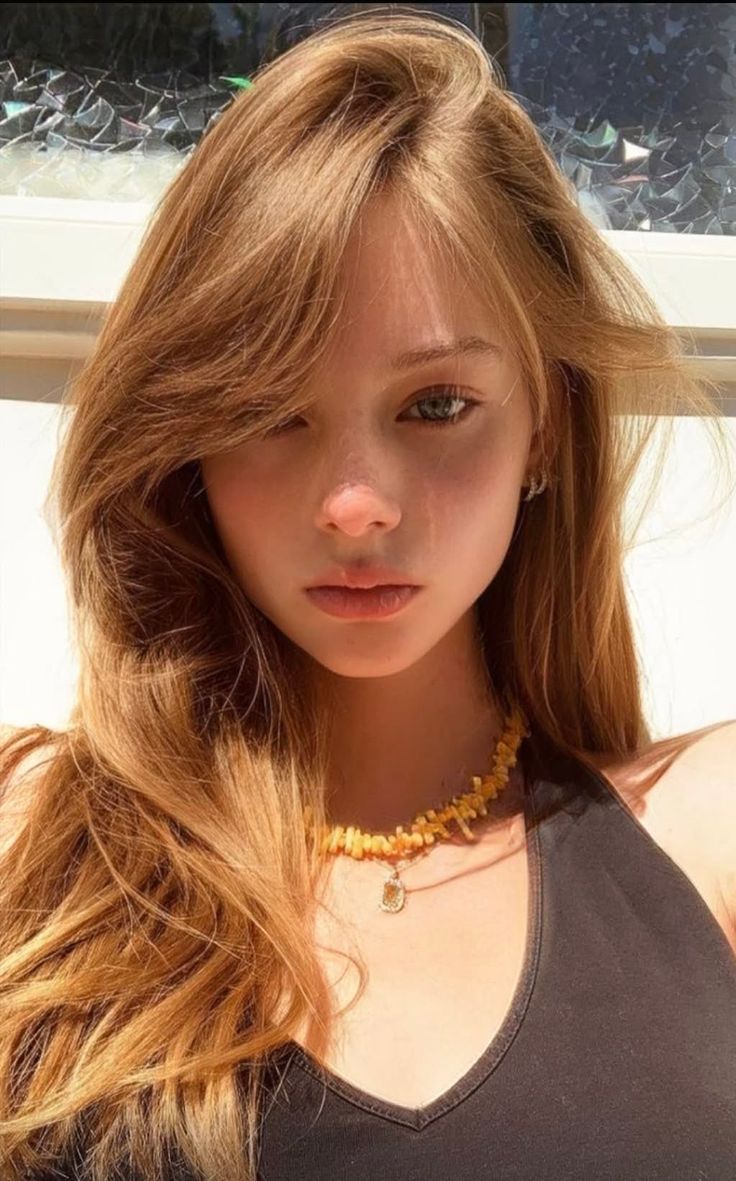 Young woman with long blonde hair and a yellow necklace in daylight